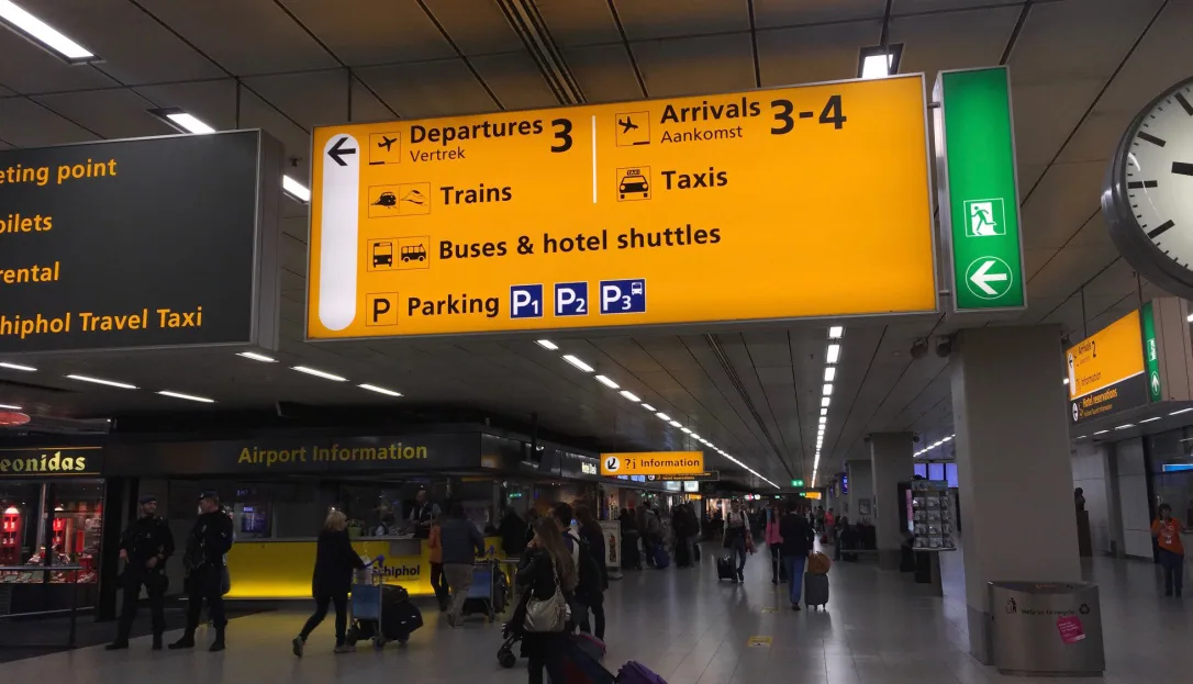 Yellow train signs inside the arrivals hall at Schiphol Airport